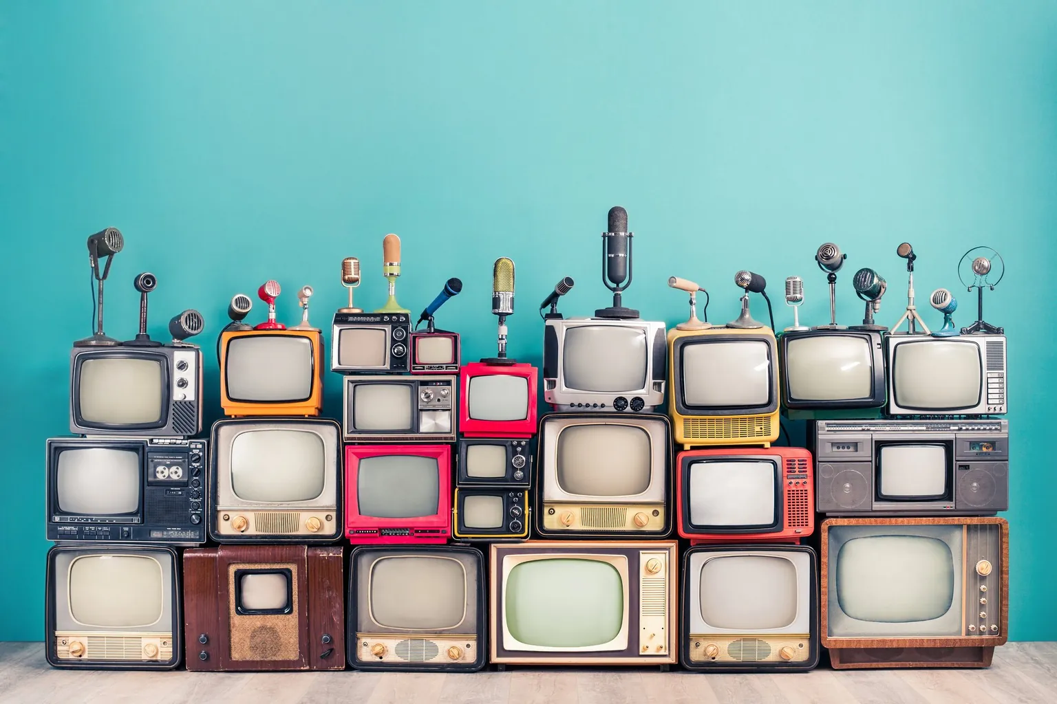 Many vintage televisions, stacked