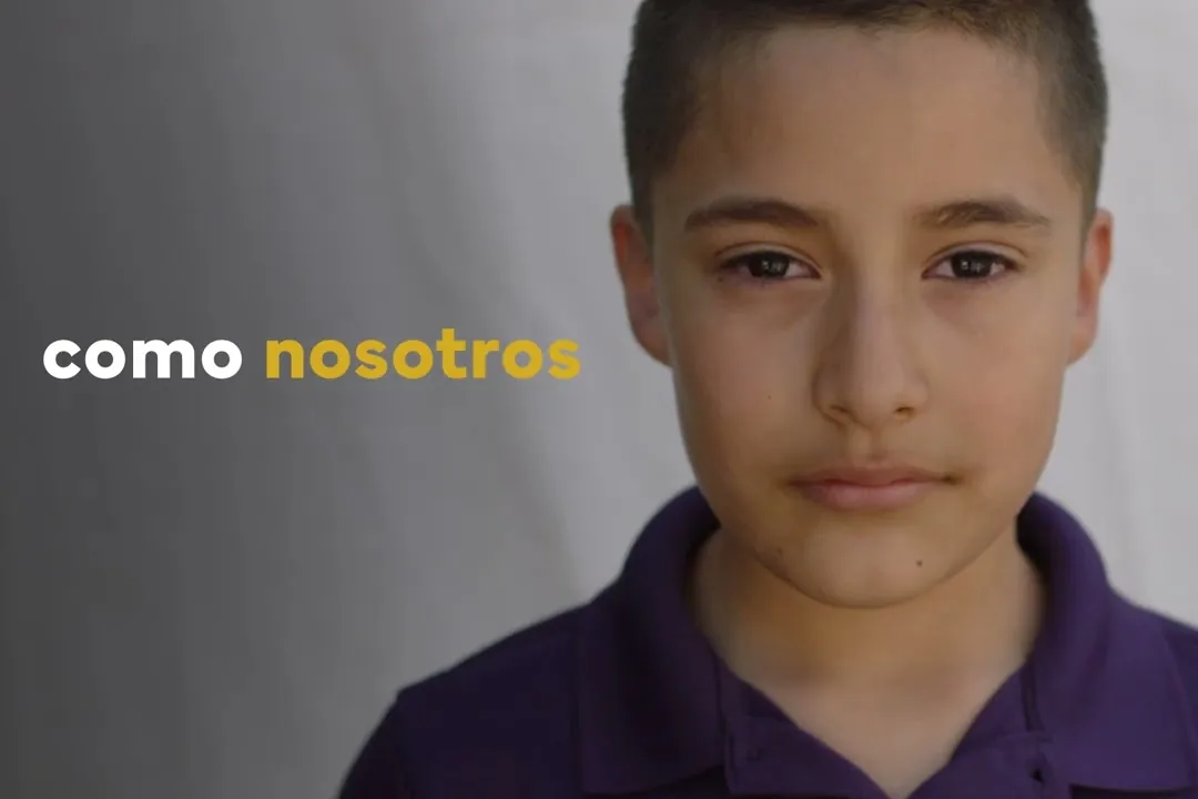A boy in a purple shirt looks at camera, with the Spanish caption 'como nosotros'
